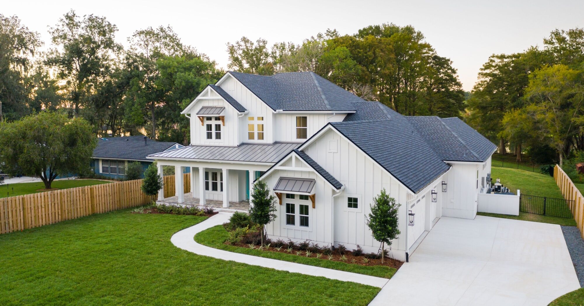 A white, two-story new construction home with modern and well-kept landscaping.